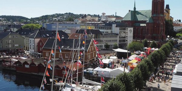 

Promenade med flotte seilbåter med norske flagg, trær og sol 