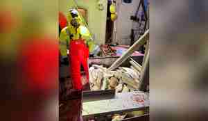 foto av mann i oljehyre med bord fullt av torsk