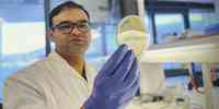 

A scientist in a lab, holding a petridish with samples.