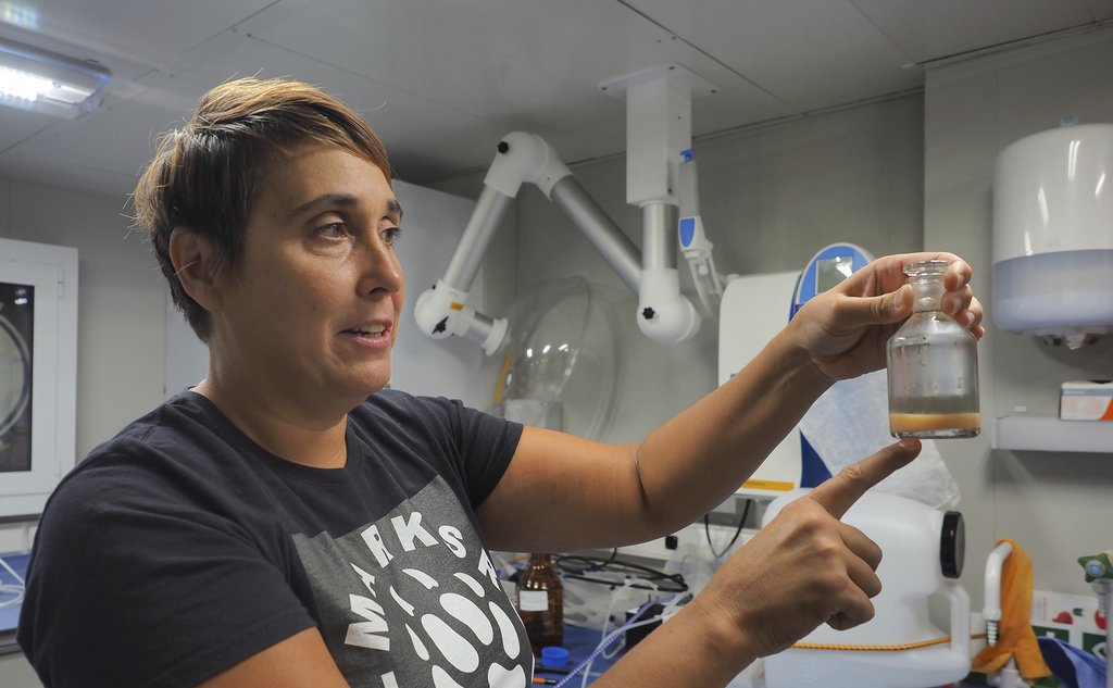 Havforsker Melissa Chierici viser frem en vannprøve i en liten flaske, mens hun peker på den. 