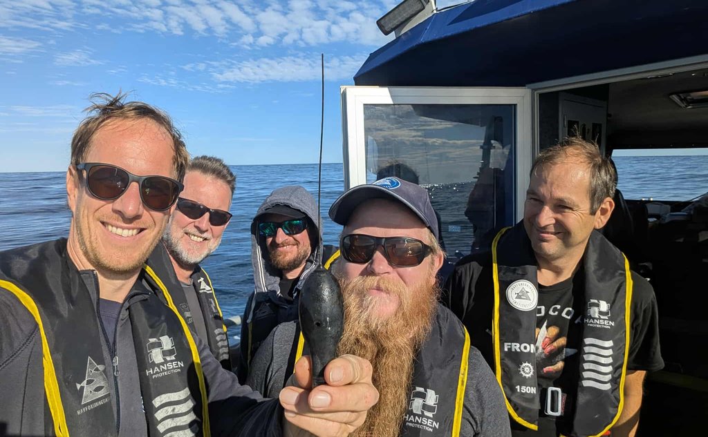 foto av fem menn i en båt som holder fram en dings