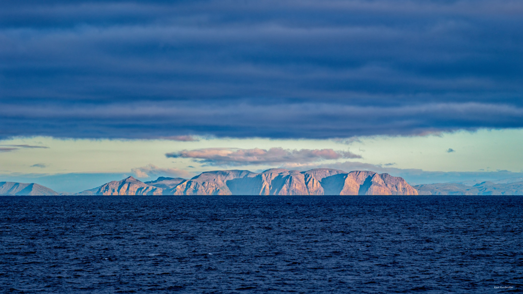 utsikt over blått hav med isfjell i horisonten