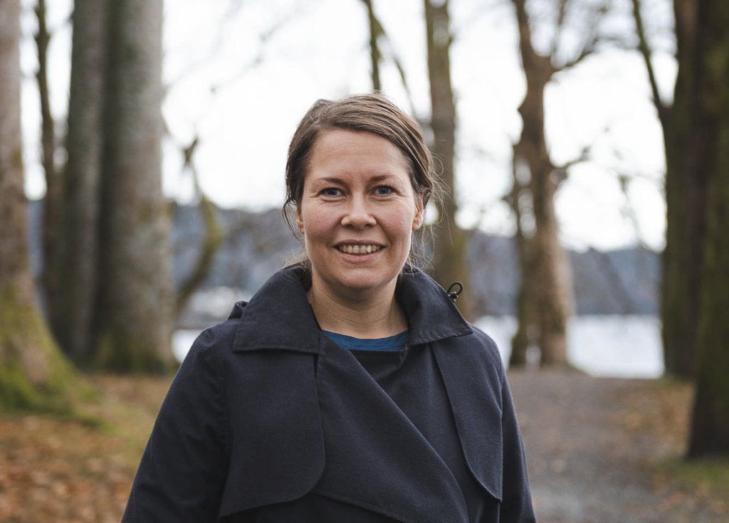 smilende kvinne utendørs med blå himmel bak