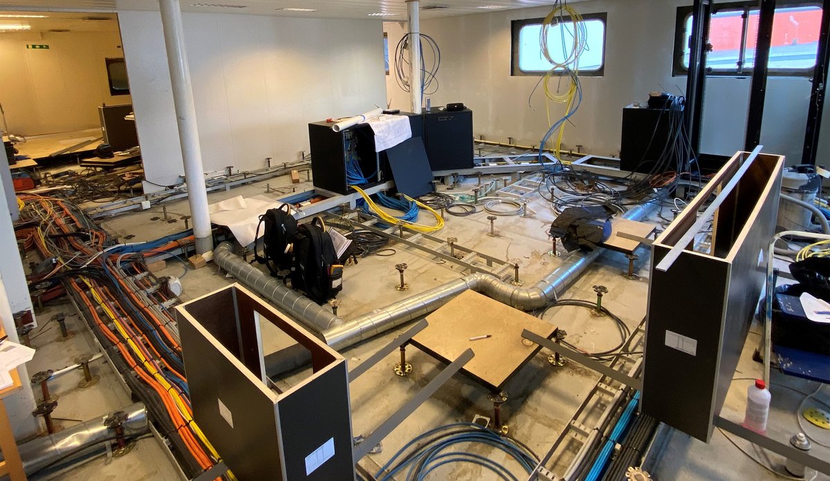 Rom på fartøy med røyr, ledningar og diverse utstyr liggande framme under arbeid.