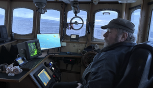 foto av mann i styrhuset på sjark